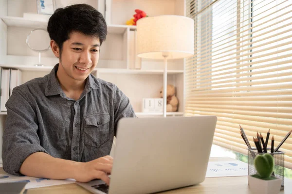 Adam ofisteki dizüstü bilgisayarında oturmuş yüzünde kararlı bir ifadeyle ev konforuyla çalışıyor, erkek eli dizüstü bilgisayara basıyor, evden çalışıyor..