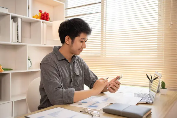 Genç adam cep telefonunda gülümseyen yüzüyle sohbet ya da mesaj yazıyor, Smartphone 'da gülen yüz, dijital iletişim, internet ağının akıllı telefonu aracılığıyla sohbet mesajı yazıyor..