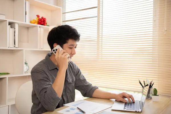 Young male businessman talks on the phone with a customer to negotiate business, Long distance communication, Negotiating a Business Deal via Phone Call.