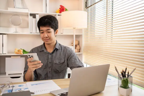 Genç adam cep telefonunda gülümseyen yüzüyle sohbet ya da mesaj yazıyor, Smartphone 'da gülen yüz, dijital iletişim, internet ağının akıllı telefonu aracılığıyla sohbet mesajı yazıyor..