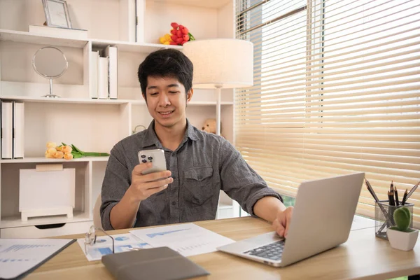 Genç adam cep telefonunda gülümseyen yüzüyle sohbet ya da mesaj yazıyor, Smartphone 'da gülen yüz, dijital iletişim, internet ağının akıllı telefonu aracılığıyla sohbet mesajı yazıyor..