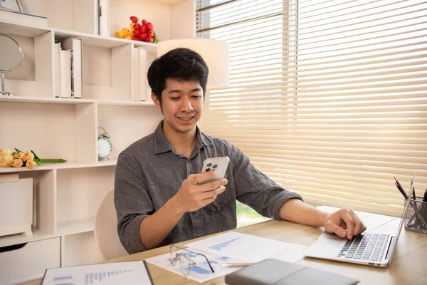 Genç adam cep telefonunda gülümseyen yüzüyle sohbet ya da mesaj yazıyor, Smartphone 'da gülen yüz, dijital iletişim, internet ağının akıllı telefonu aracılığıyla sohbet mesajı yazıyor..