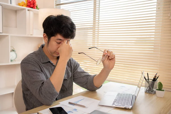 Yorgun genç adam gözlerini uzun ekran süresinden dinlendiriyor, göz yorgunluğu ve stres atağı, göz yorgunluğu semptomları, iş yorgunluğu, Dijital Göz Gerilimi.