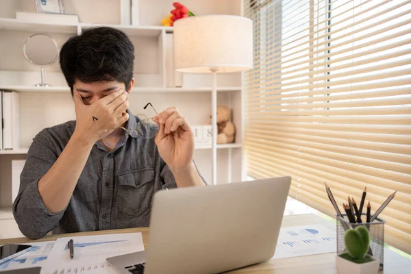 Yorgun genç adam gözlerini uzun ekran süresinden dinlendiriyor, göz yorgunluğu ve stres atağı, göz yorgunluğu semptomları, iş yorgunluğu, Dijital Göz Gerilimi.