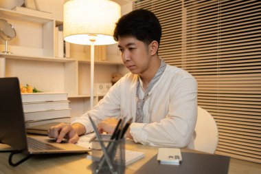 Gecenin bir yarısı çalışan bir adam, ofisinde dizüstü bilgisayarında oturmuş yüzünde kararlı bir ifadeyle, dizüstü bilgisayara basan bir erkek eliyle....