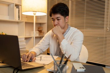 Gecenin bir yarısı çalışan bir adam, ofisinde dizüstü bilgisayarında oturmuş yüzünde kararlı bir ifadeyle, dizüstü bilgisayara basan bir erkek eliyle....