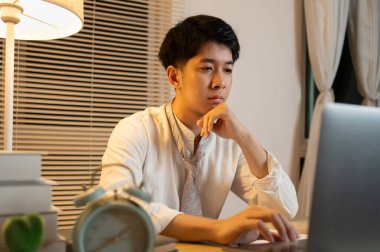 Gecenin bir yarısı çalışan bir adam, ofisinde dizüstü bilgisayarında oturmuş yüzünde kararlı bir ifadeyle, dizüstü bilgisayara basan bir erkek eliyle....