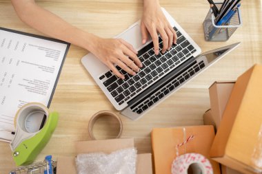 Dizüstü bilgisayardaki el sıkışmasının üst görünümü, bilgisayarla iletişim kurmak için yazı yazma sohbeti, bilgisayardaki parmak tıklama ve mesajlaşma, çevrimiçi satış, paketleme kutusu.