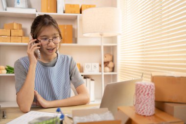 Çevrimiçi ürünleri sat, çevrimiçi alışveriş şirketi sahibi telefonda teslimat adresini ve teslimat programını, KOBİ girişimcisinin online alışverişini, paketleme kutusunu, serbest çalışma programını yazmak için bir müşteriyle konuşuyor..