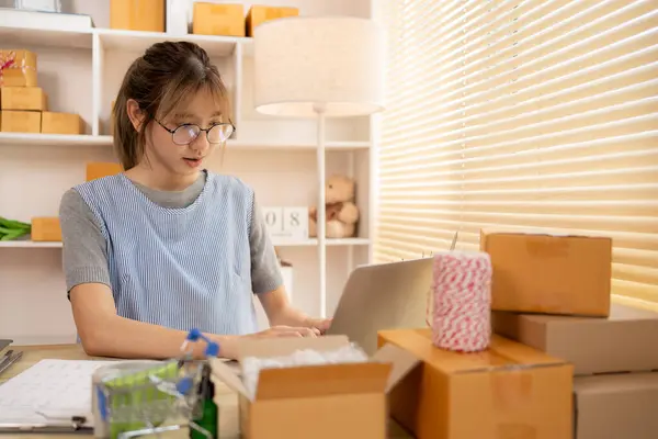 Online selling, Young woman uses a laptop to type and chat with a customer, Send products online ,Work-from-Home SME Owner Thrives in Online Sales, Packing Box.