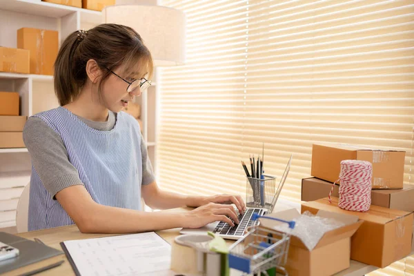 Online selling, Young woman uses a laptop to type and chat with a customer, Send products online ,Work-from-Home SME Owner Thrives in Online Sales, Packing Box.