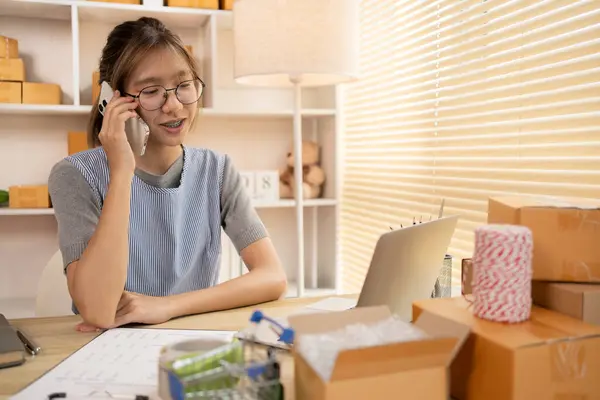 Sell products online, Online shopping business owner is talking on the phone with a customer to jot down the delivery address and delivery schedule, SME entrepreneur online shopping, Packaging box, Work freelance.