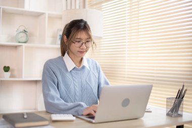 Dizüstü bilgisayarın önünde yazan bir kadın, dizüstü bilgisayara basan bir el bilgisayarı, ofiste çalışmak isteyen bir kadın..