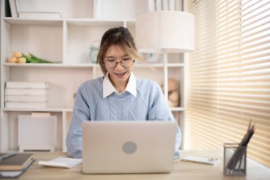 Dizüstü bilgisayarın önünde yazan bir kadın, dizüstü bilgisayara basan bir el bilgisayarı, ofiste çalışmak isteyen bir kadın..