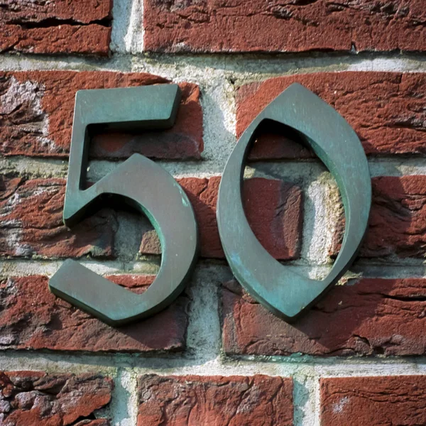 レンガの壁に取り付けられたブロンズハウスナンバー50 — ストック写真