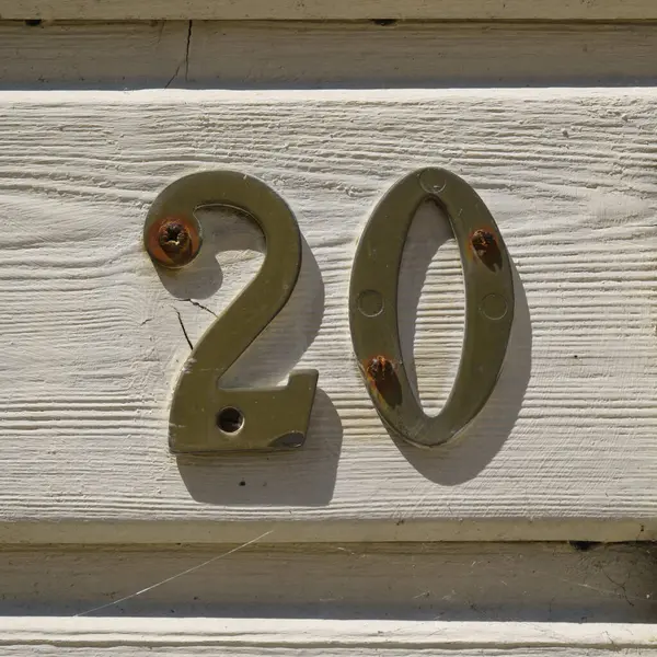 20 (20) numaralı pirinç ev tahtadan bir panelde.