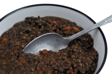 Beyaz arka planda kaşıkla pişirilmiş mercimek tabağı. 