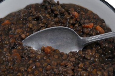 Bir kaşıkla yakın plan pişirilmiş mercimek tabağı. 