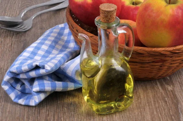 Carafe of apple vinegar with a basket of apples close-up