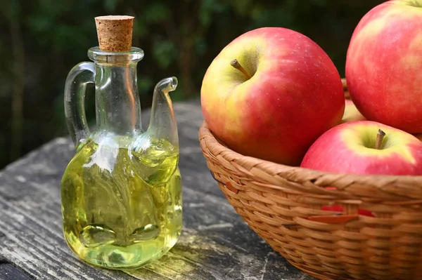Carafe of apple vinegar with a basket of apples close-up
