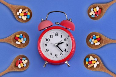 Çalar saat ahşap kaşıklarla çevrili ve çeşitli uyuşturucular var. 