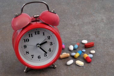 Gri arka planda çeşitli uyuşturucu içeren alarmlı saat