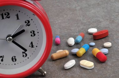 Gri arka planda çeşitli uyuşturucular içeren alarmlı saat 