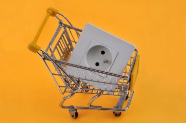 Bir süpermarket tramvayında elektrik prizi olan elektrik gideri kavramı sarı arka planda kapanıyor