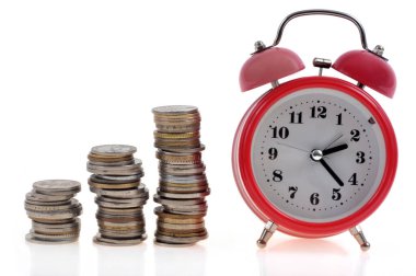 Beyaz zemin üzerinde bozuk para yığınları olan klasik alarm saati