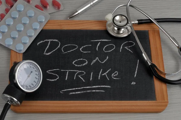 Doctor on strike written on a school slate surrounded by medical instruments