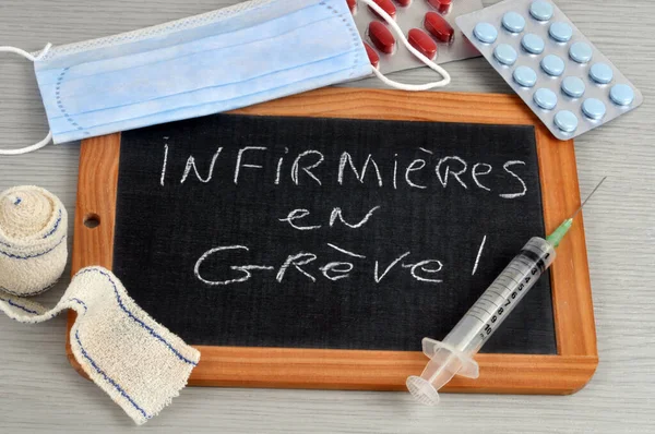 Nurses on strike written in french on a school slate surrounded by medical instruments