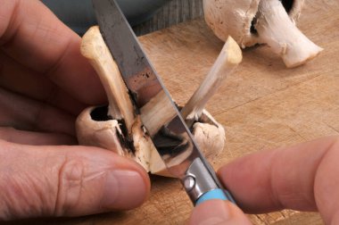 Cutting a button mushroom with a knife close-up