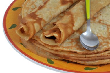 Krep üzerine yuvarlanmış krepler bir tabakta, kaşıkla yakın plan beyaz arka plan.