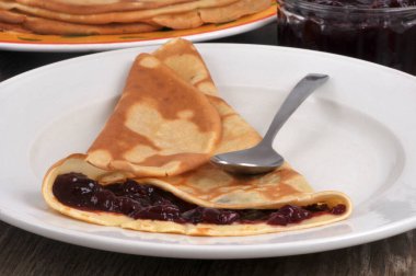 Reçelli ev yapımı krep, kaşıkla bir tabakta üçgen şeklinde katlanmış.