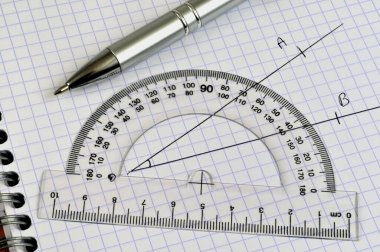 Measuring an angle with a protractor and a pen lying on a notebook close up