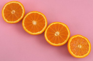 Cut oranges on pink background