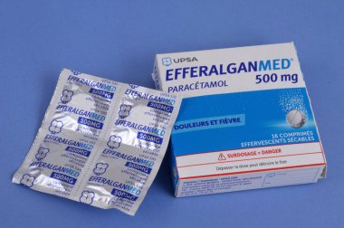 Box of Efferalgan 500 and sachet of effervescent tablets in their packaging close up on a blue background