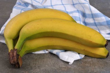 Organic bananas with a kitchen towel close-up on a gray background