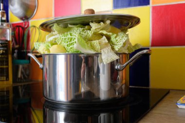 Dutch oven filled with vegetables with a lid on a hob close-up 