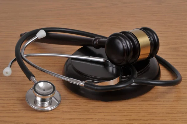 Medical error concept with a stethoscope and a judge gavel on wooden background