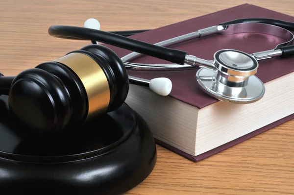 Medical error concept with a stethoscope lying on a book and a judge gavel close-up