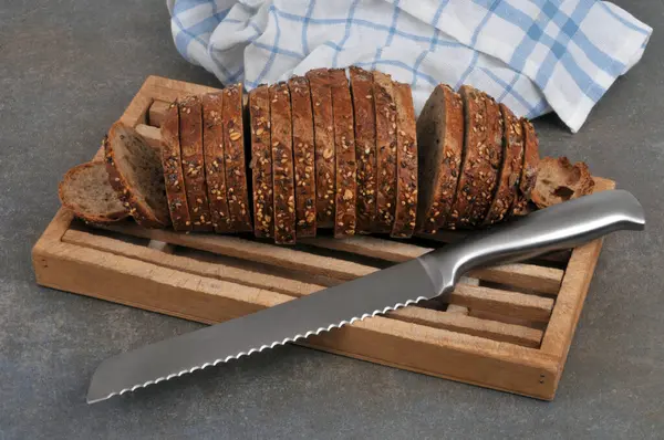 ナイフで木のまな板に種パンをスライス — ストック写真