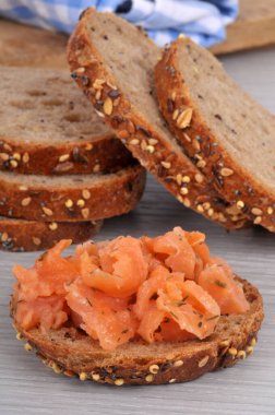 Arka planda tohum ekmeği tostu olan alabalıklı tost.