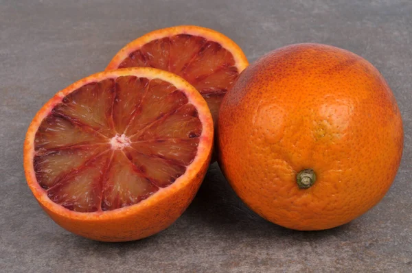 血のオレンジは半分に切り 血のオレンジは灰色の背景で閉じます — ストック写真