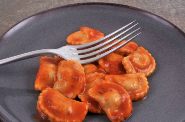 Domates soslu ravioli tabağı ve çatal yakın plan.