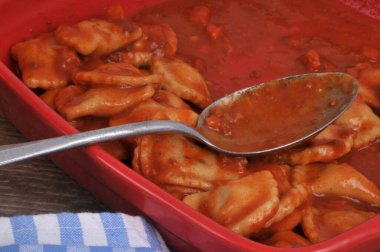 Domates soslu ravioli tabağı kaşıkla yakın plan.