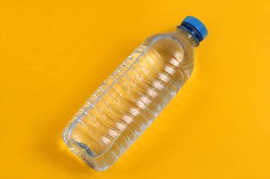 Plastik maden suyu şişesi sarı arkaplanı kapatır. 