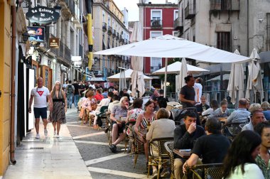 Alicante 'de bir caddede restoran teraslarında oturan turistler