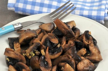 Mantarlar, yakın plan çatallı bir tabakta sarımsakla pişirilir.