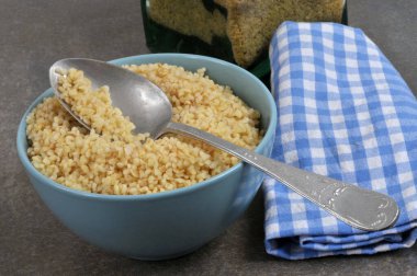 Bir kase bulgur, kaşık ve peçeteyle yakın plan.